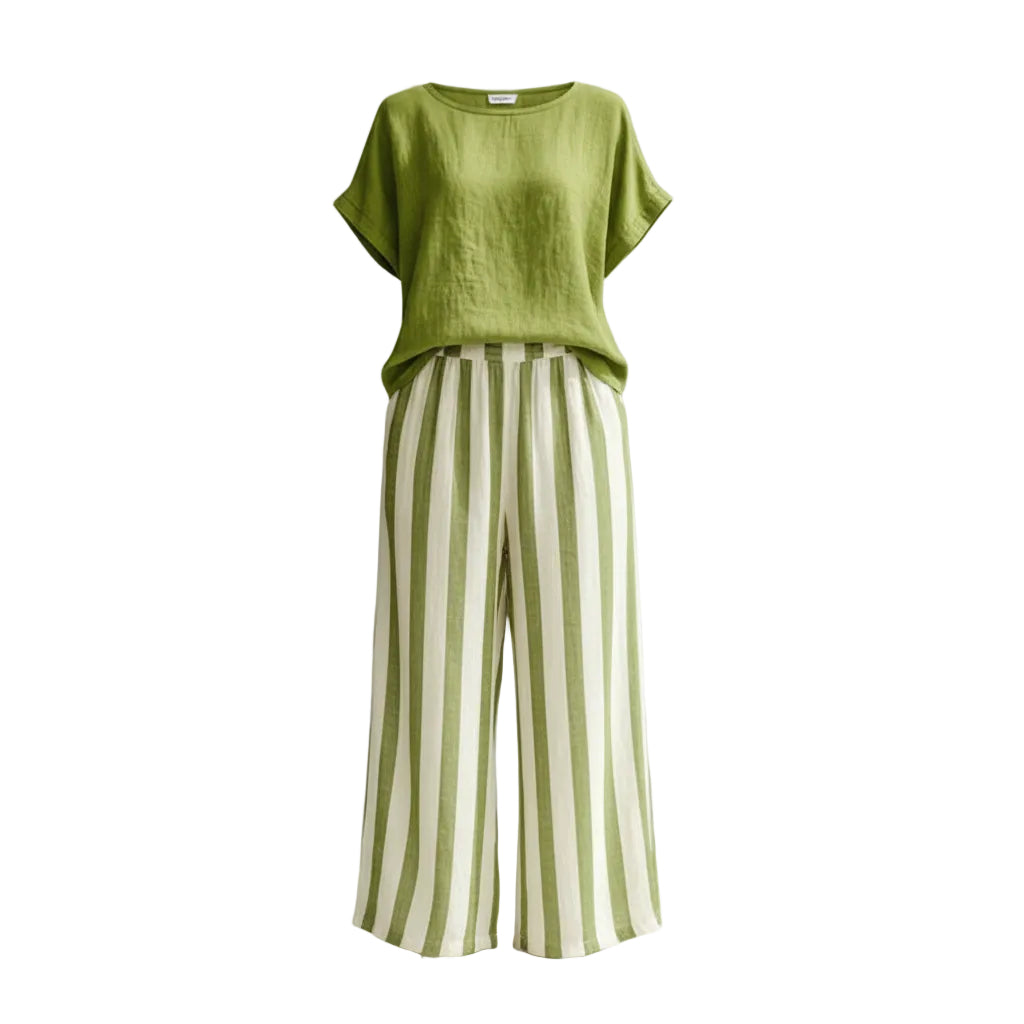 Woman wearing a green top and striped pants against a gray background