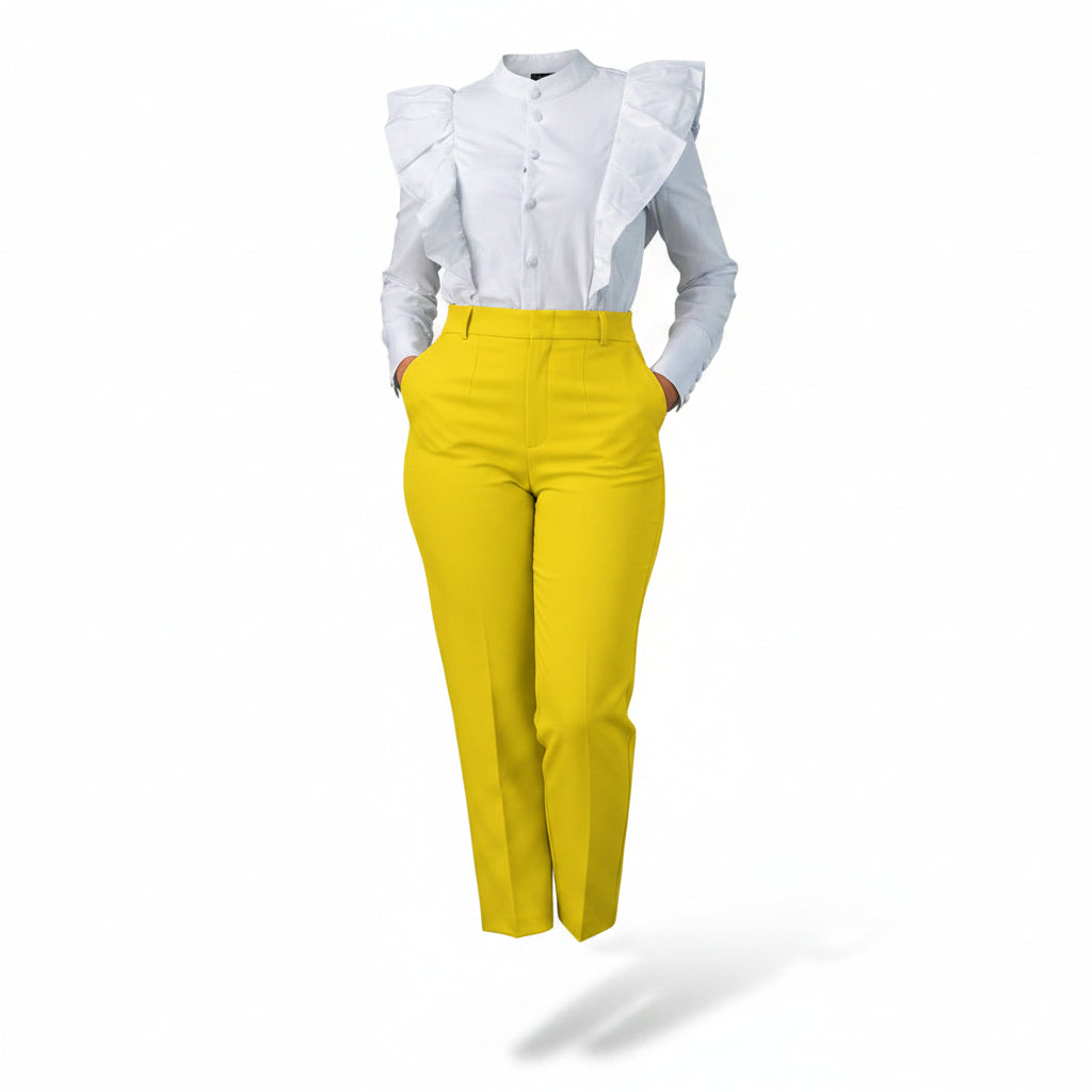 Person wearing a light blue blouse with ruffled details and yellow pants against a concrete wall.