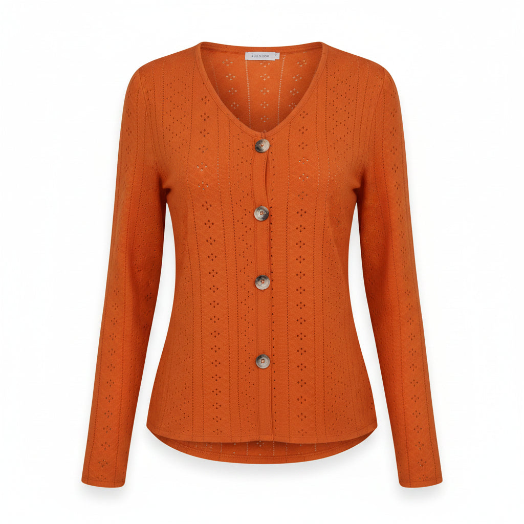 A woman wearing a bright orange long-sleeve V-neck cardigan with decorative eyelet embroidery and four large buttons, paired with blue jeans.