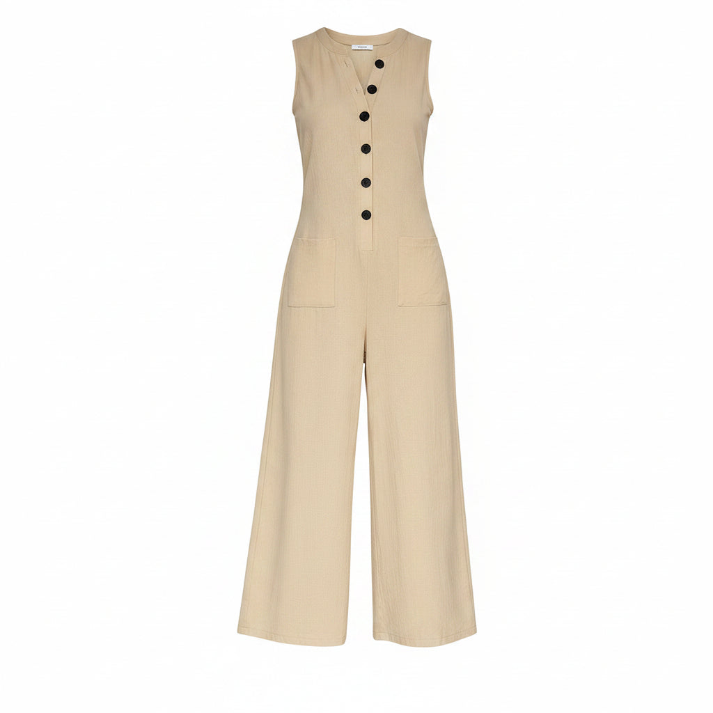 Woman wearing a beige jumpsuit with black buttons in a home setting.