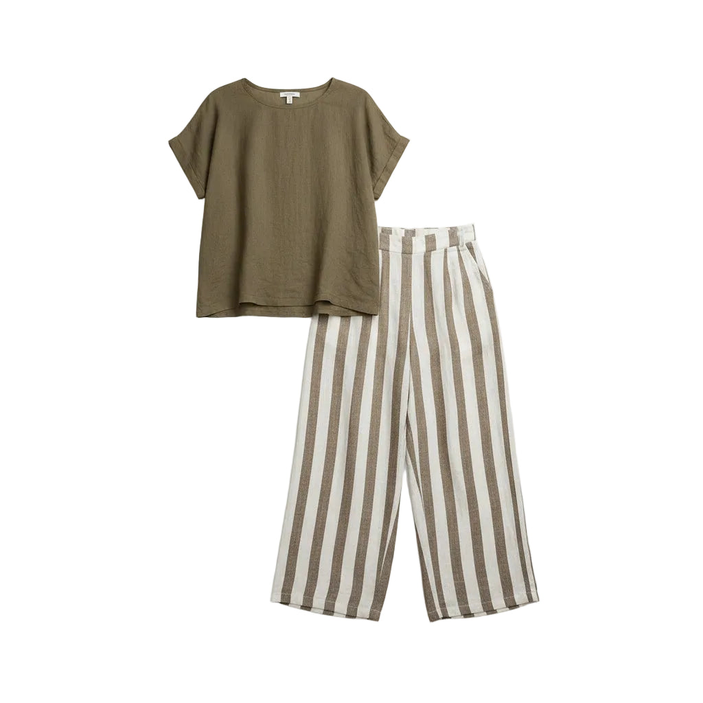 Woman wearing a green top and striped pants against a gray background