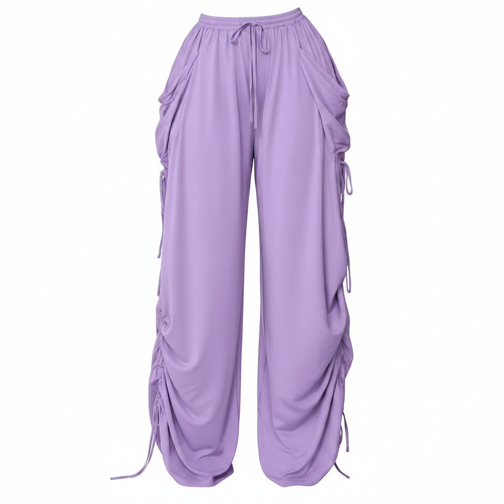 A person wearing loose, wide-leg lavender pants with drawstrings, side pockets, and ruched detailing down the legs, holding a small black handbag. The photo is cropped from the waist down against a plain indoor wall and floor, with text in the top right reading 'Drawstring Plus Size'.